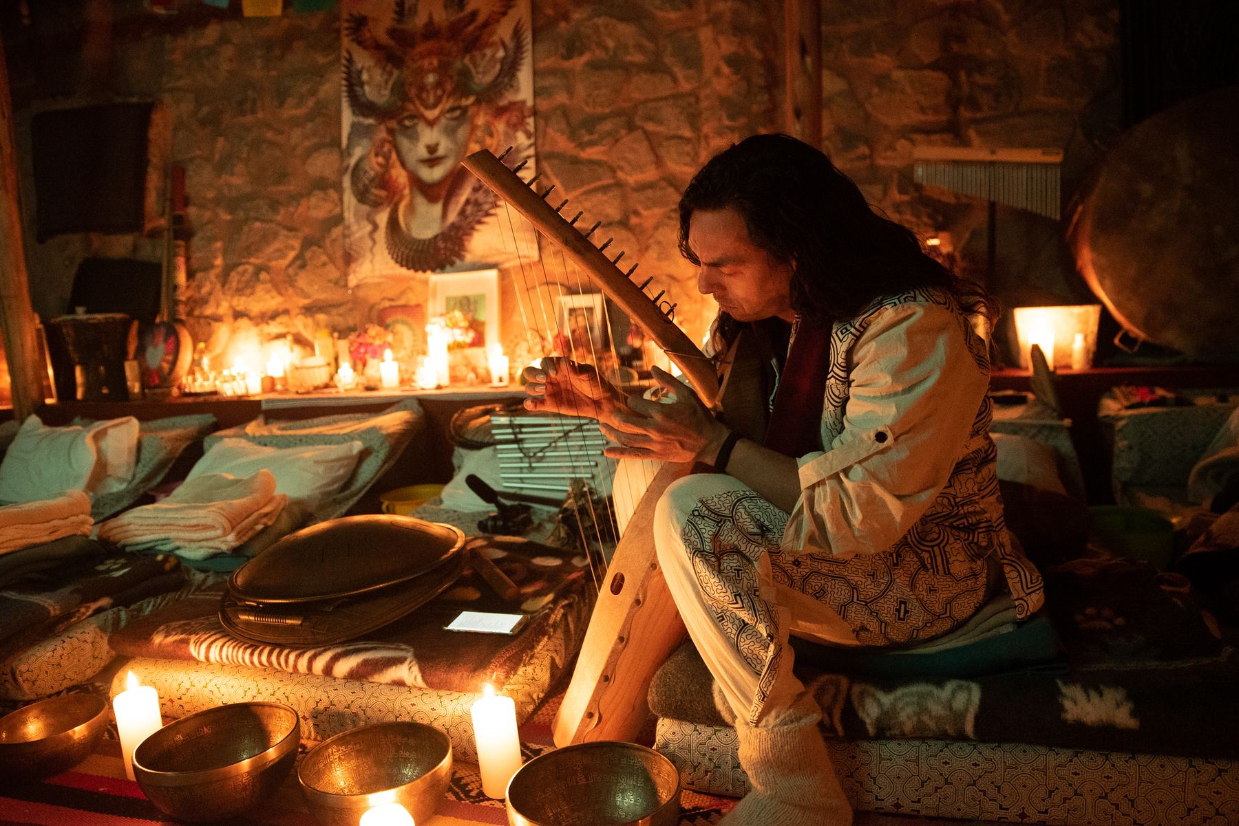 A musician playing beside the candle-lit altar and singing bowls