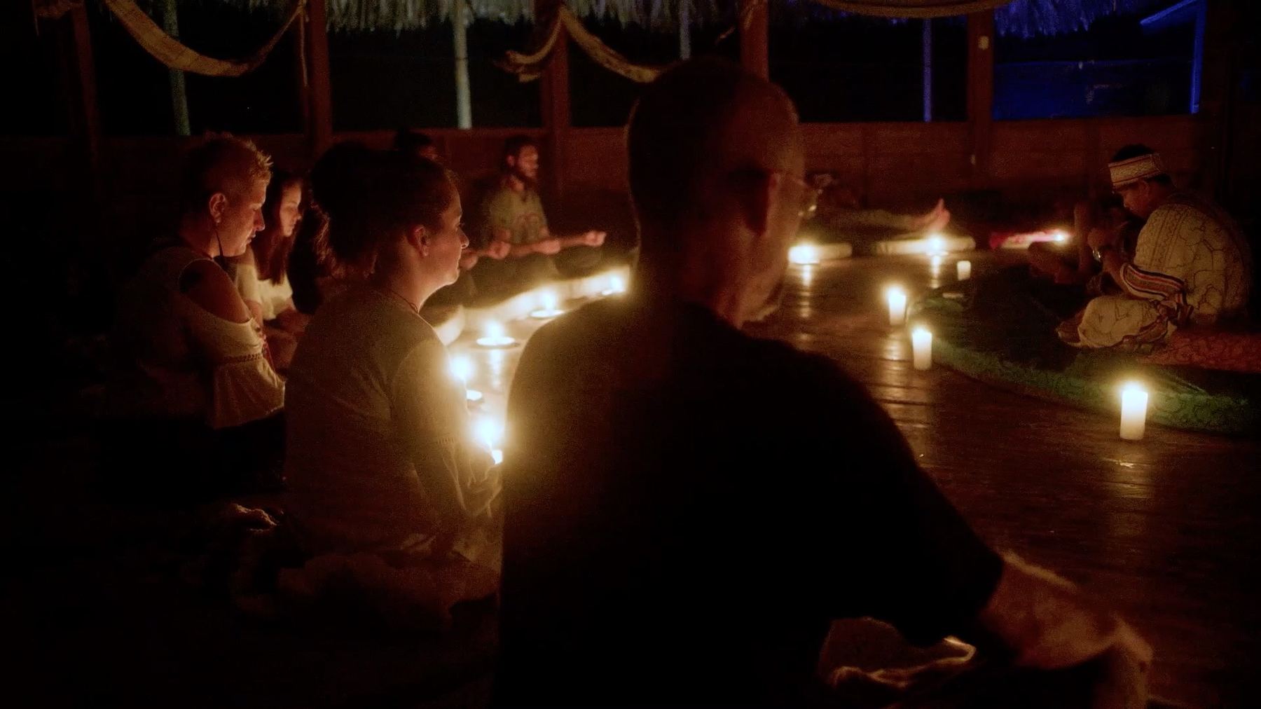 Guests seated in meditation around a candle-lit ceremonial circle