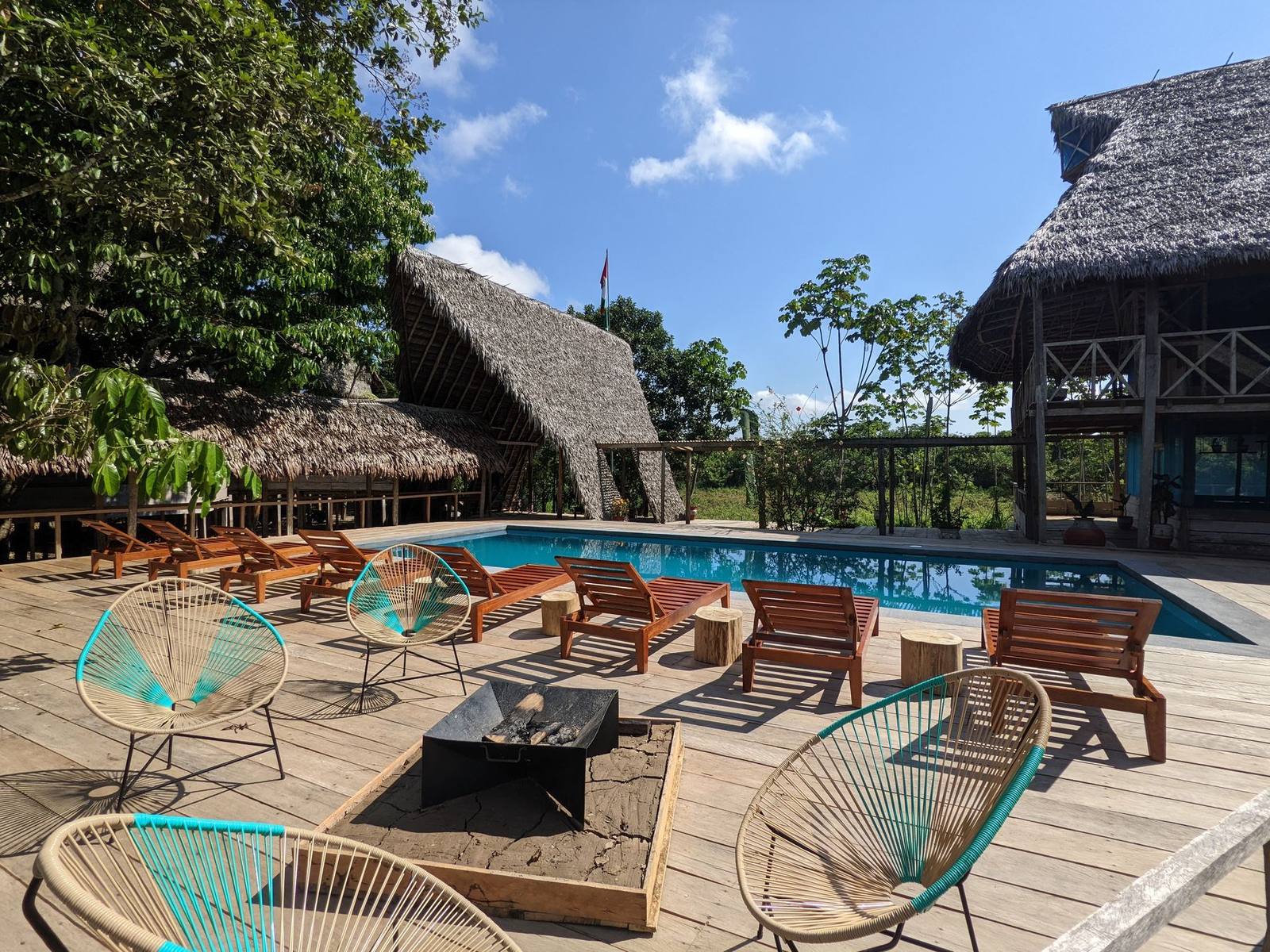 Pool deck with loungers beneath thatched roofs