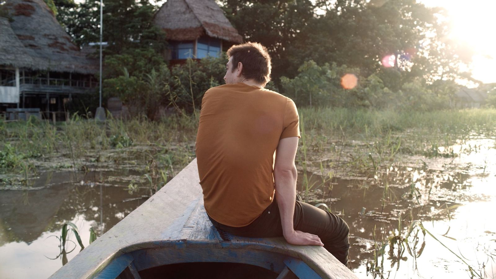 A guest resting at the bow of a canoe on the river at sunset