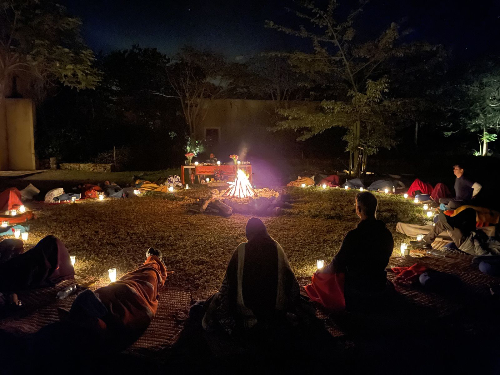 Guests resting around a ceremonial fire in the hacienda gardens at night
