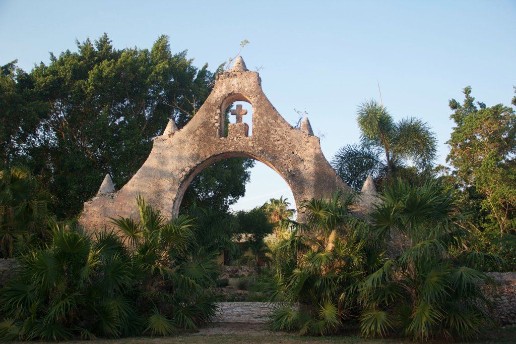 The hacienda’s old stone archway and bell, framed by palms